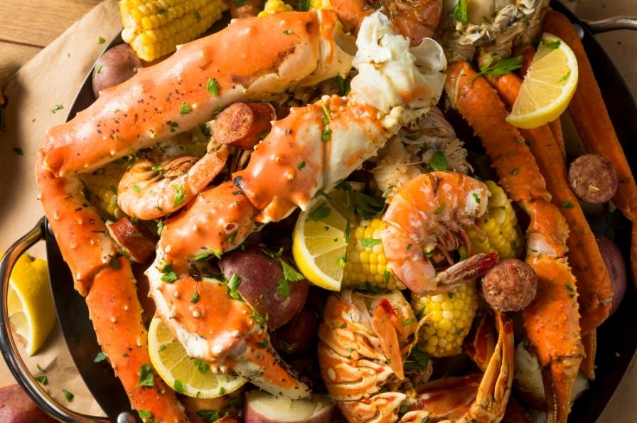 Un plat de crabes, de crevettes, de langoustes et de mais décoré avec des cartier de citron jaune et du persil