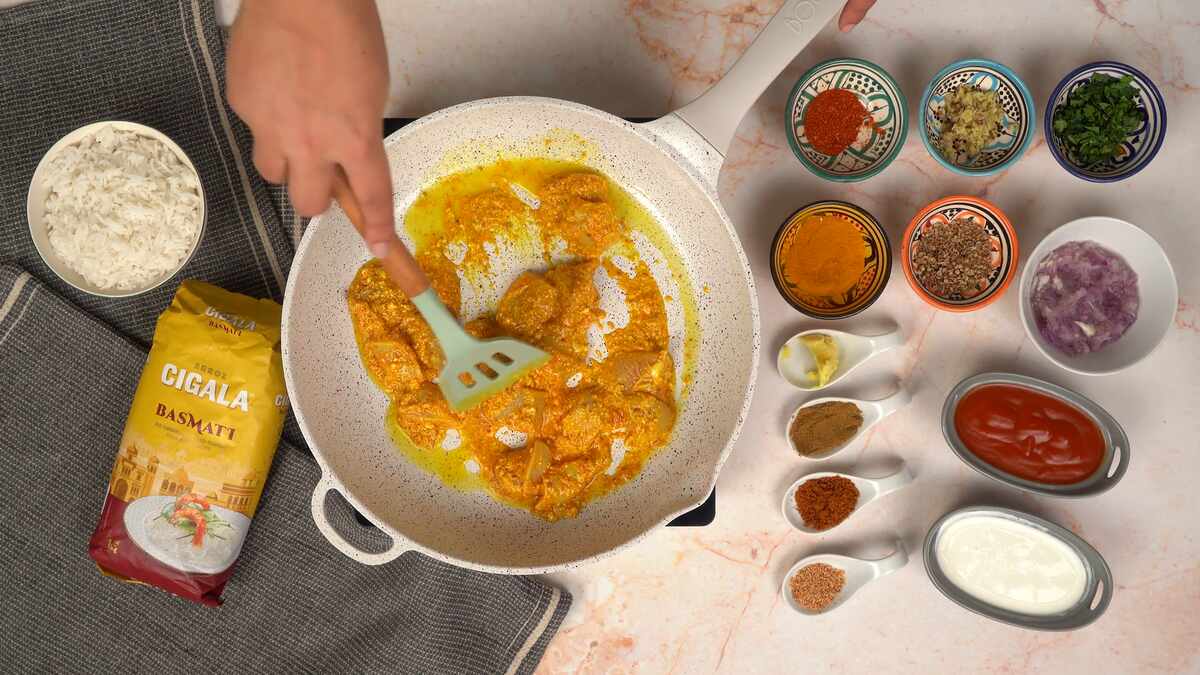 cuisson du poulet mariné de la tikka masala dans une poêle blanche 