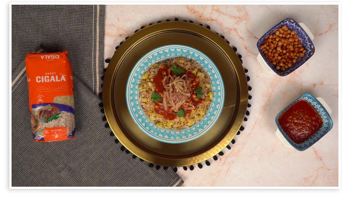 Présentation du plat égyptien; le koshari, avec la sauce tomate épicée et les pois chiches